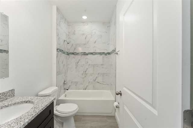 full bathroom featuring vanity, wood-type flooring, tiled shower / bath combo, and toilet