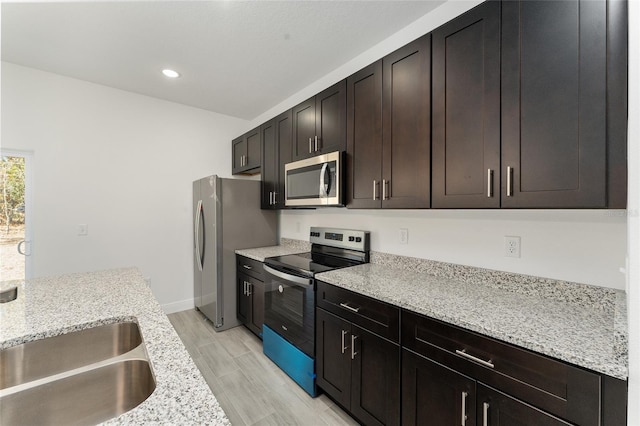 kitchen featuring dark brown cabinetry, light stone countertops, light hardwood / wood-style floors, and appliances with stainless steel finishes