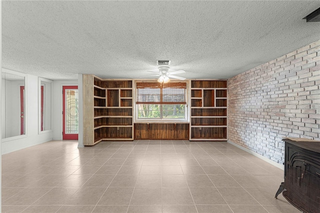 unfurnished living room featuring light tile patterned floors, a wood stove, and brick wall