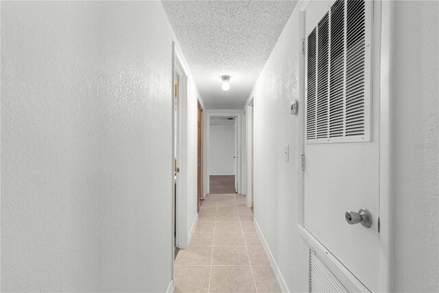 hall featuring light tile patterned flooring and a textured ceiling