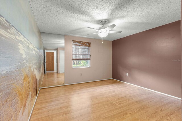 empty room with ceiling fan, light hardwood / wood-style flooring, and a textured ceiling