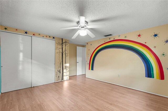 unfurnished bedroom with ceiling fan, a textured ceiling, light hardwood / wood-style floors, and a closet