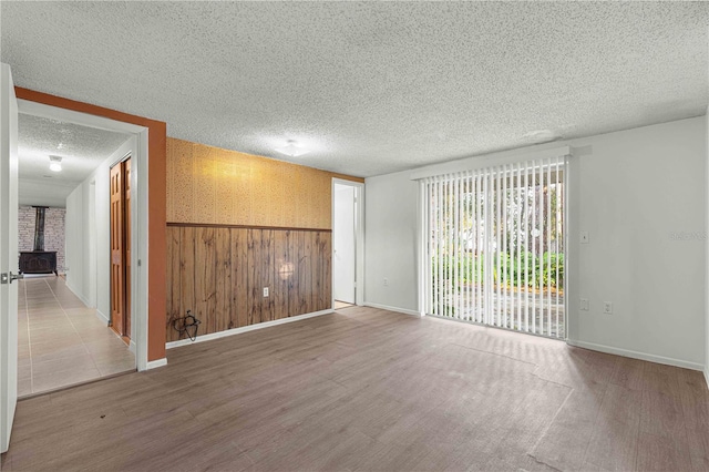 spare room with hardwood / wood-style floors, a wood stove, a textured ceiling, and brick wall