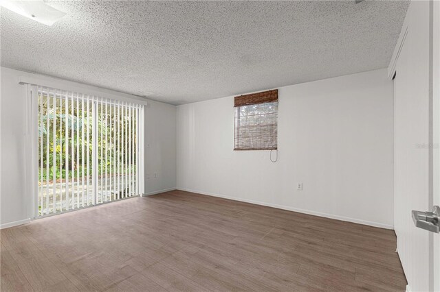 spare room with a wealth of natural light, a textured ceiling, and hardwood / wood-style floors