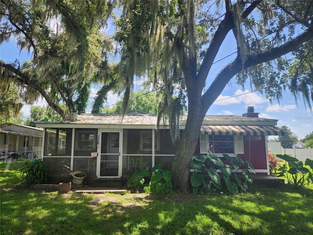 rear view of house with a lawn and a sunroom