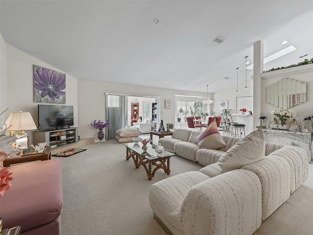 living area with light colored carpet, visible vents, and vaulted ceiling with skylight