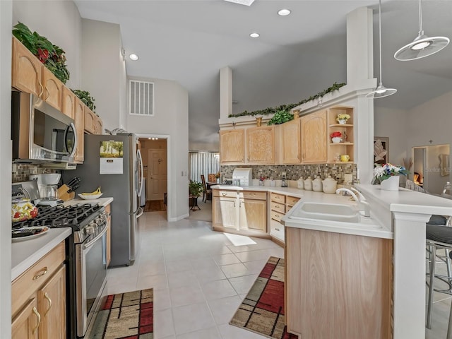 kitchen with stainless steel appliances, light brown cabinetry, a peninsula, and light countertops