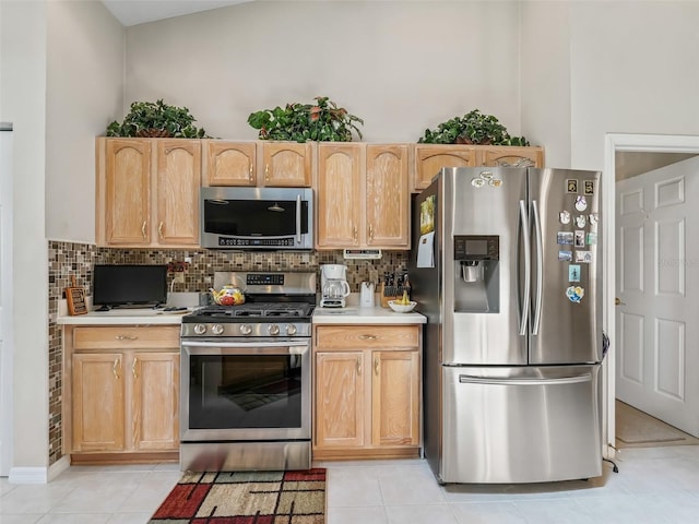 kitchen with light brown cabinets, appliances with stainless steel finishes, light countertops, and backsplash