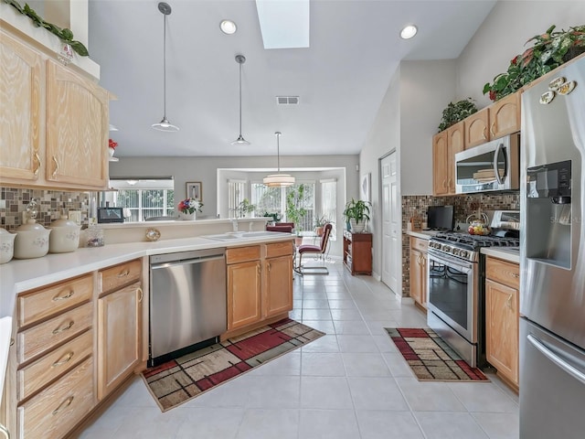 kitchen featuring stainless steel appliances, visible vents, light countertops, light brown cabinetry, and decorative light fixtures