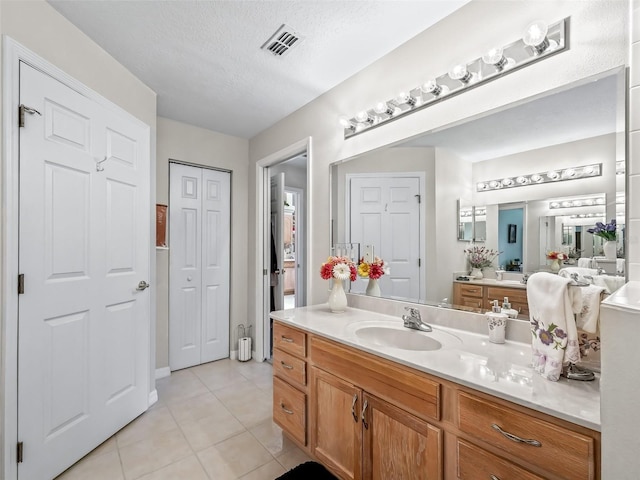 full bath with visible vents, tile patterned floors, a textured ceiling, vanity, and a closet