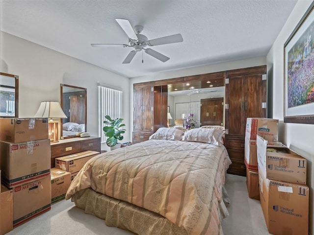 bedroom with ceiling fan, a textured ceiling, and light colored carpet