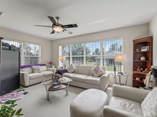 carpeted living room with ceiling fan and visible vents