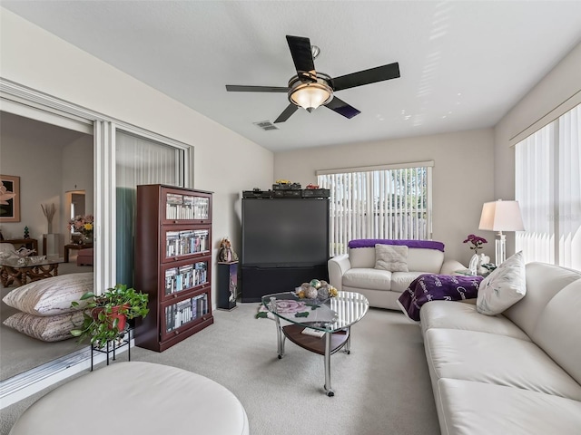 living area with a ceiling fan, visible vents, and light colored carpet