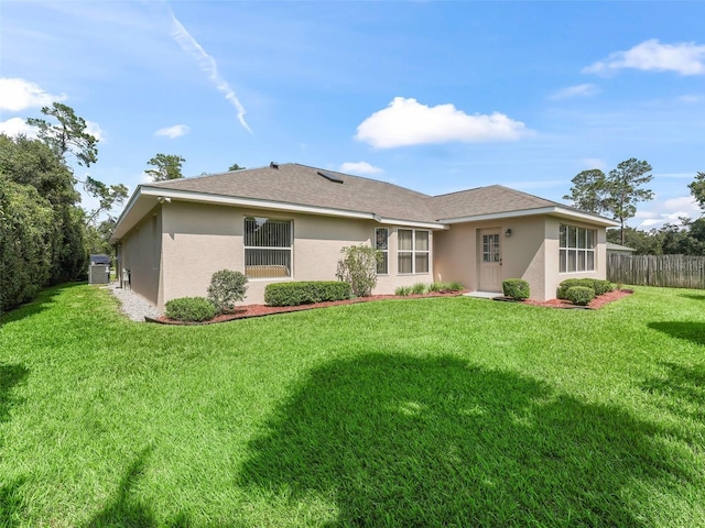 back of property featuring a lawn, fence, and stucco siding