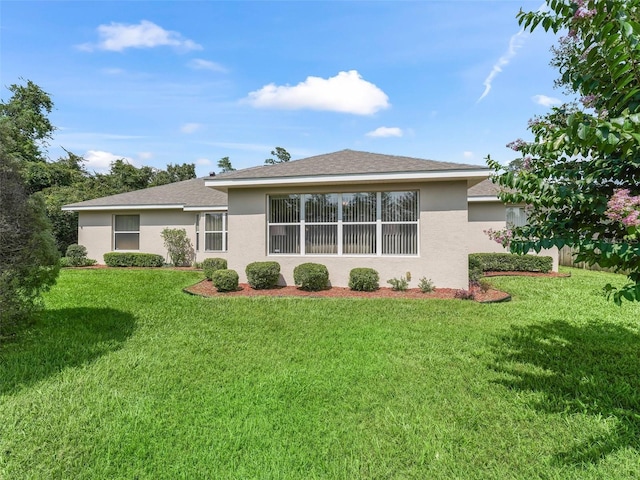 back of property with roof with shingles, a lawn, and stucco siding