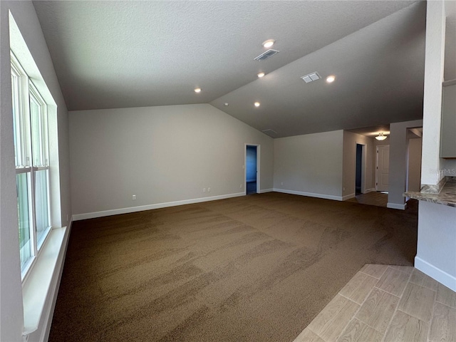 unfurnished living room featuring a textured ceiling, light colored carpet, and lofted ceiling