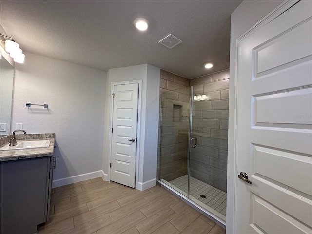 bathroom featuring vanity, an enclosed shower, and a textured ceiling