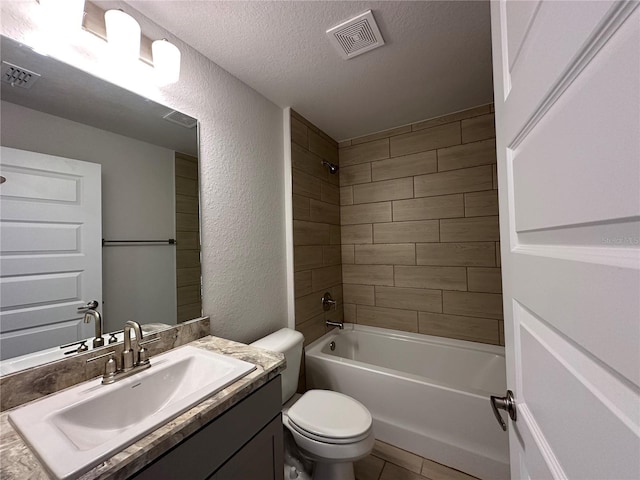 full bathroom with vanity, tile patterned flooring, tiled shower / bath combo, toilet, and a textured ceiling