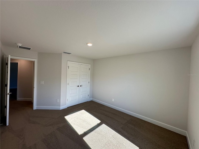 unfurnished bedroom featuring a closet and dark colored carpet