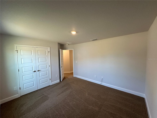 unfurnished bedroom featuring dark colored carpet and a closet