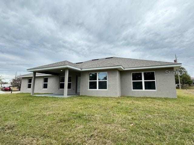 back of property with a lawn and a patio