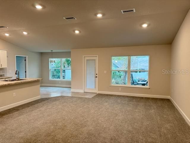 carpeted spare room with sink and vaulted ceiling