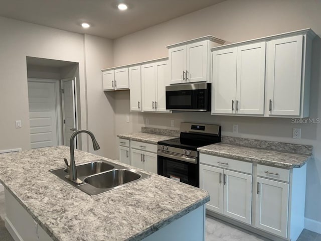 kitchen featuring sink, white cabinets, stainless steel appliances, and an island with sink