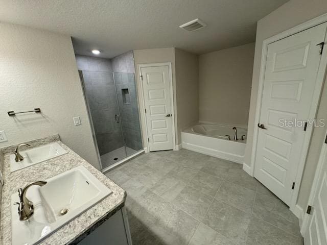 bathroom featuring vanity, independent shower and bath, and a textured ceiling