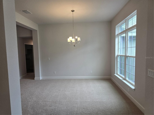 carpeted empty room with a notable chandelier