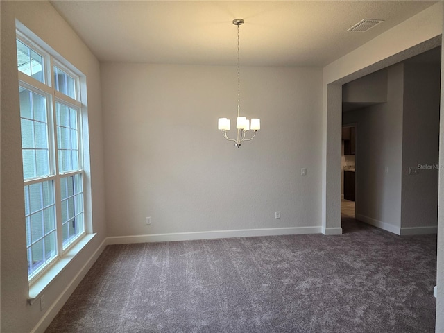 carpeted spare room with a chandelier and a healthy amount of sunlight