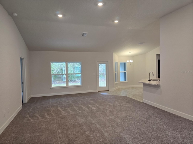 unfurnished living room with carpet flooring, sink, and a notable chandelier