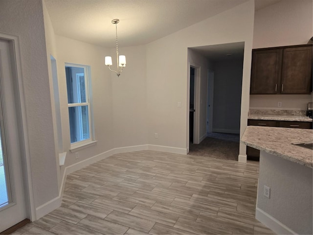 unfurnished dining area with lofted ceiling and a chandelier