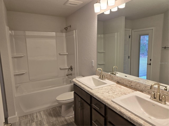 full bathroom featuring vanity, a textured ceiling, shower / bathtub combination, and toilet