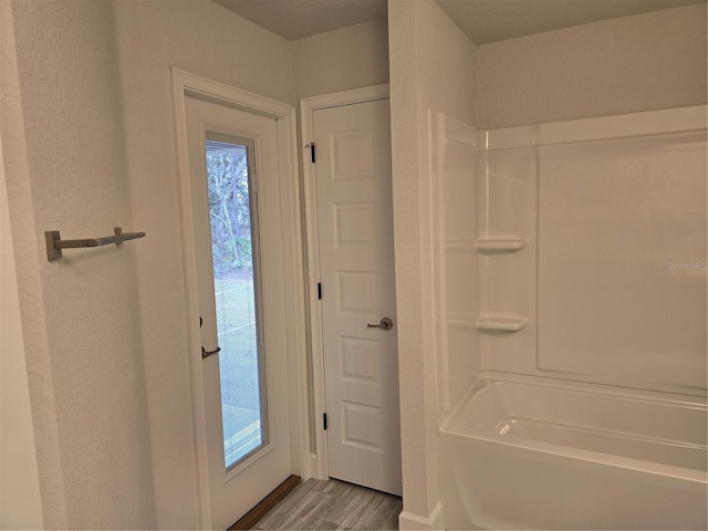 bathroom with a healthy amount of sunlight, bathtub / shower combination, and hardwood / wood-style floors