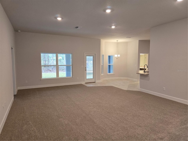 carpeted empty room featuring sink and a notable chandelier