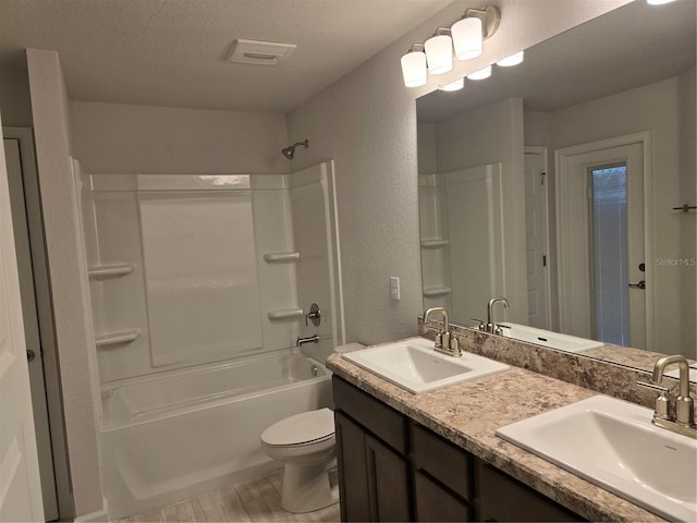 full bathroom with vanity, shower / washtub combination, a textured ceiling, and toilet