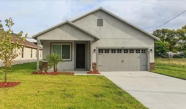 view of front of property featuring concrete driveway, an attached garage, a front lawn, and stucco siding