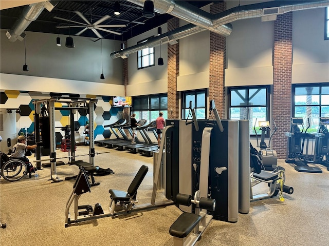 exercise room featuring brick wall and a high ceiling