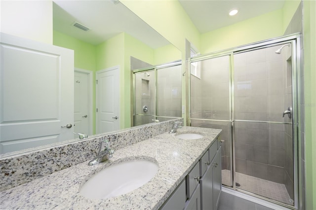 bathroom with dual vanity and a shower with door