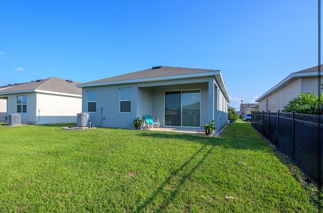 rear view of property featuring a yard, central AC unit, and a patio