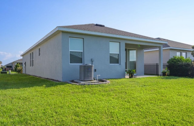 rear view of property with cooling unit and a lawn