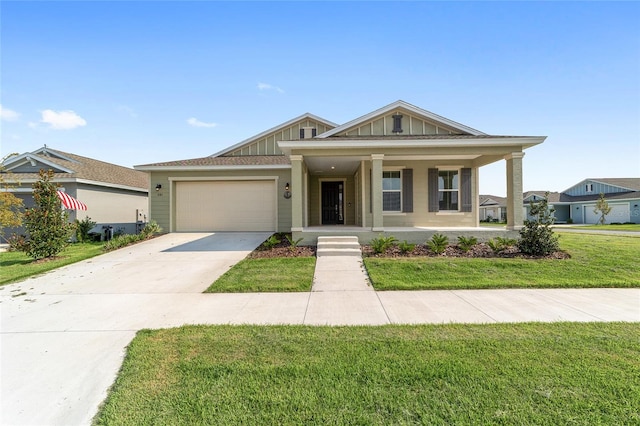 view of front of home with a front yard, covered porch, and a garage