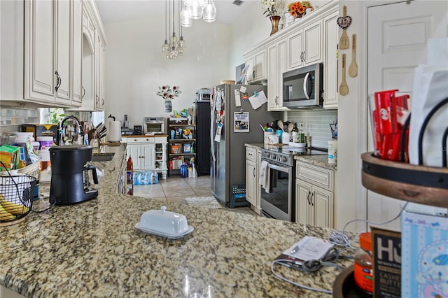 kitchen featuring an inviting chandelier, light stone counters, stainless steel appliances, light tile patterned flooring, and decorative backsplash