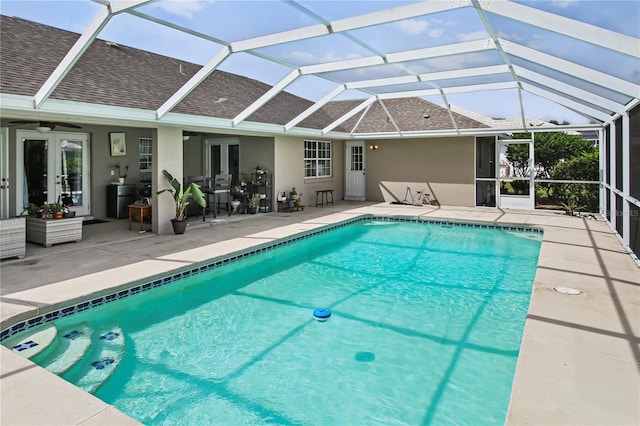 view of pool with glass enclosure, a patio, and ceiling fan