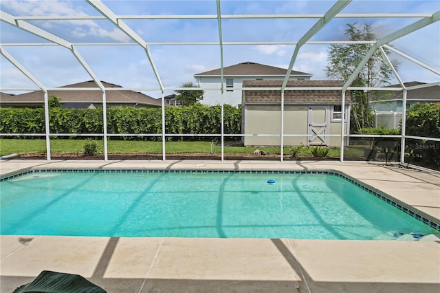 view of pool featuring glass enclosure, a patio area, and a shed