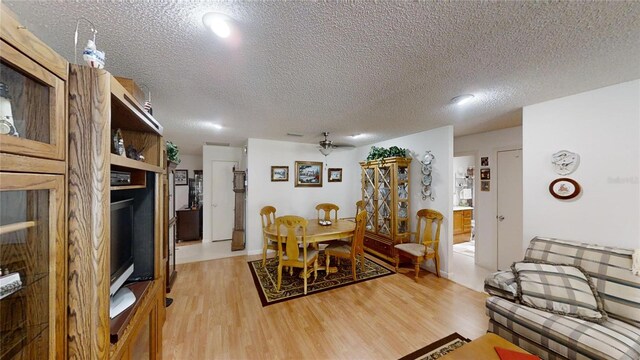 dining space featuring ceiling fan, light hardwood / wood-style flooring, and a textured ceiling