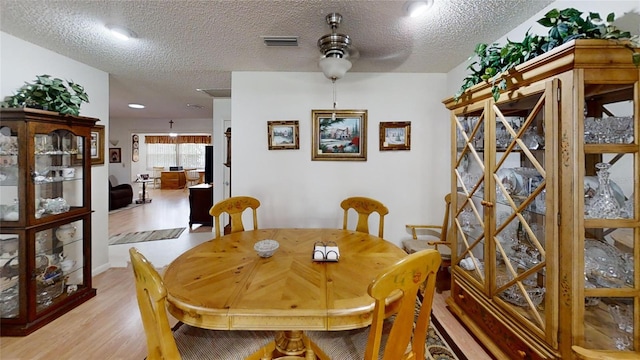 dining room featuring ceiling fan, a textured ceiling, and light hardwood / wood-style floors