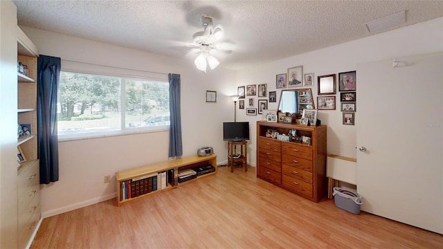 misc room with ceiling fan, a textured ceiling, and light hardwood / wood-style floors