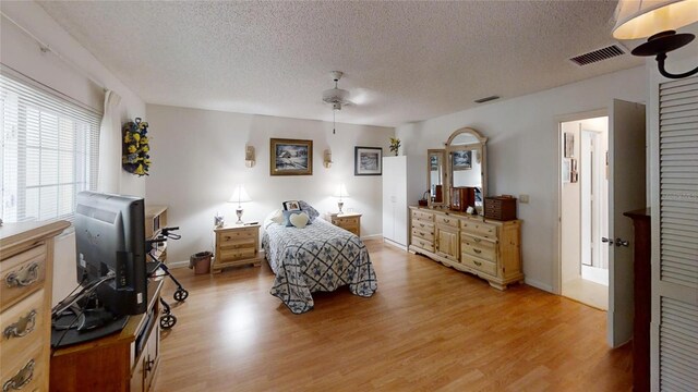 bedroom featuring light hardwood / wood-style flooring, a textured ceiling, and ceiling fan