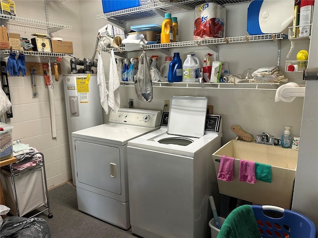 washroom with washing machine and clothes dryer, water heater, and sink